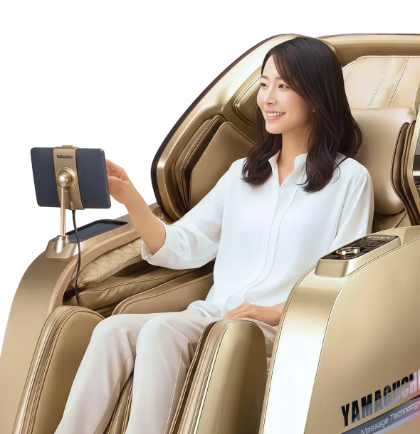 Женщина в белой рубашке сидит в золотом массажном кресле Yamaguchi Axiom, держит в руках планшет