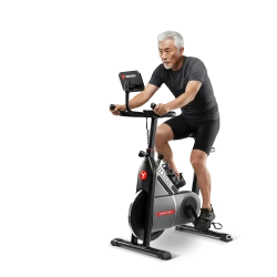 Пожилой мужчина занимается на фитнес-велотренажере Yamaguchi Fitness Bike в черной спортивной одежде