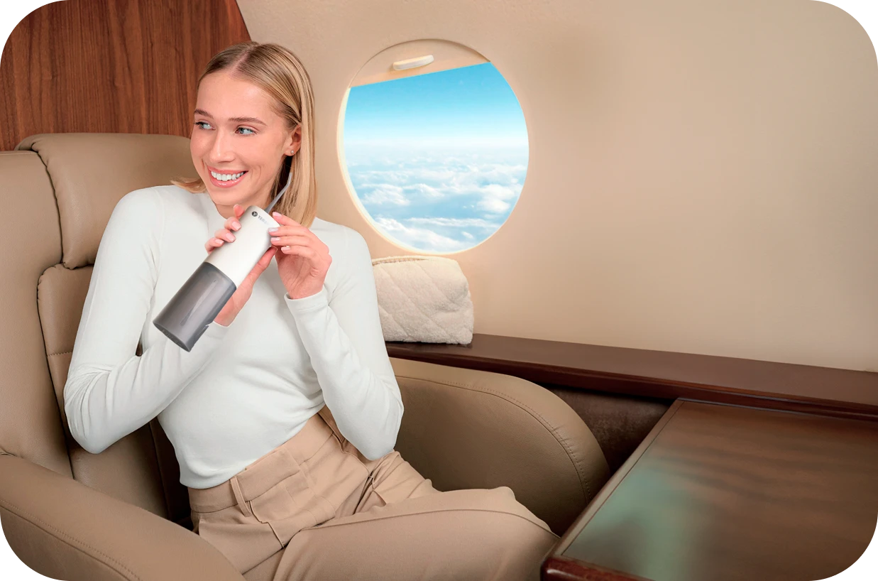 Девушка в самолете, в руках ирригатор Yamaguchi